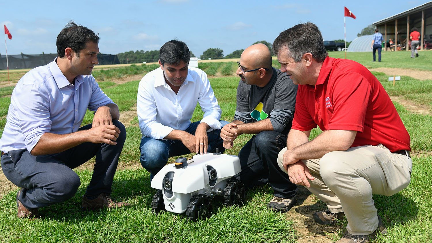Chris Reberg-Horton and Steven Mirsky, co-leaders of a $10M sustainability grant examine an autonomous ag data collection robot.