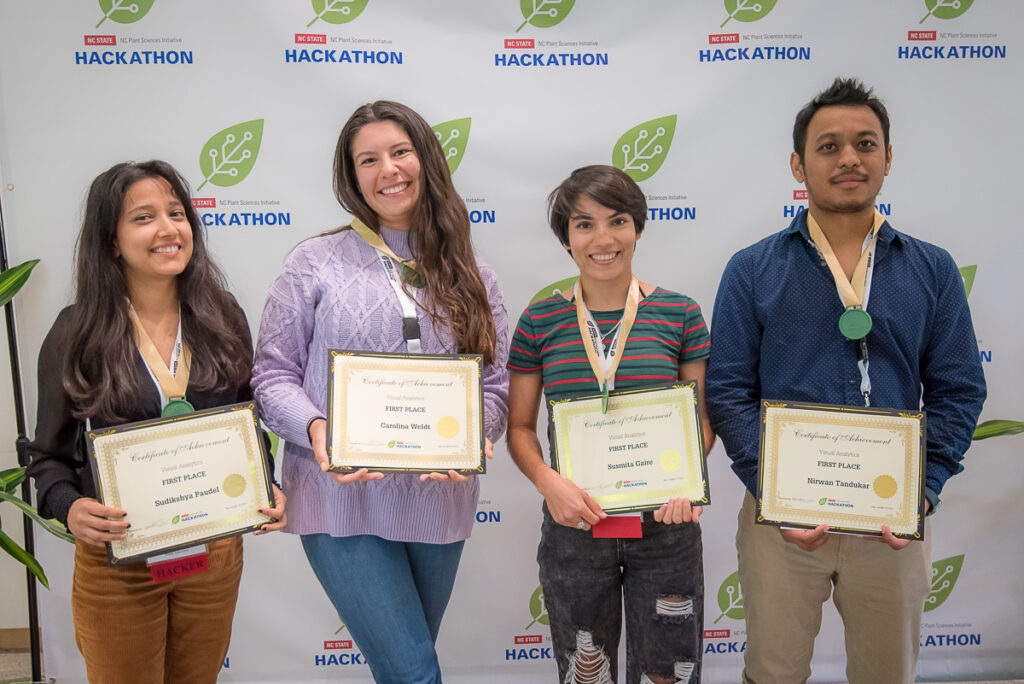 four Hackathon participants holding their first place awards