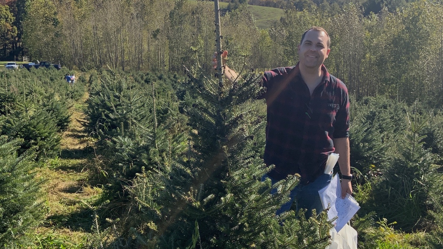 Justin Whitehill stands beside a Christmas tree