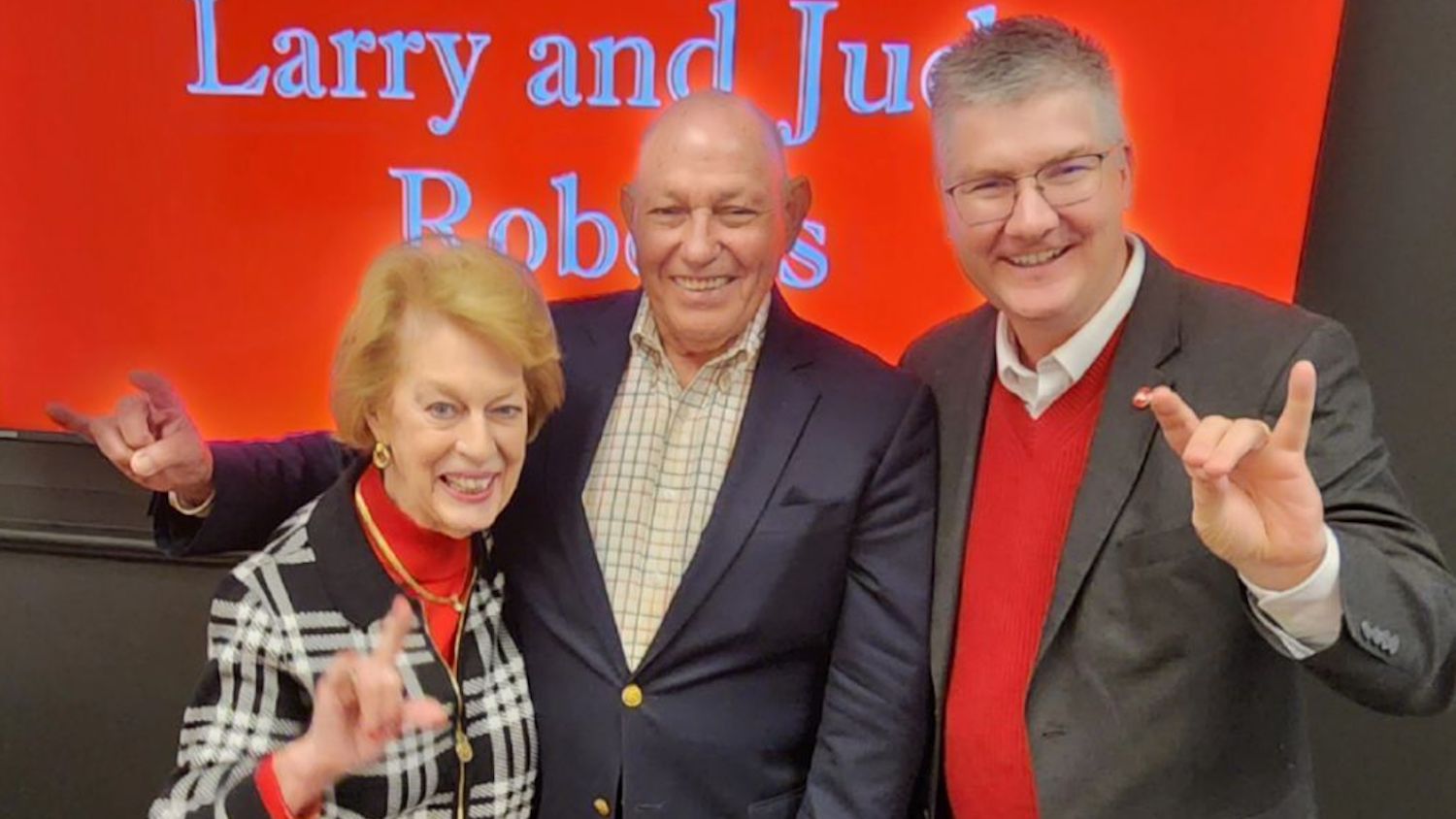 Three people, with two making the shape of a wolf with their hands