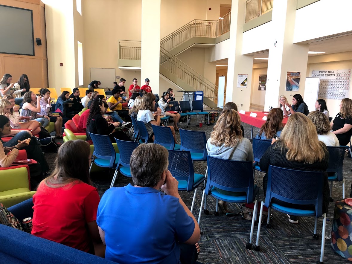 students gathered around a panel of speakers