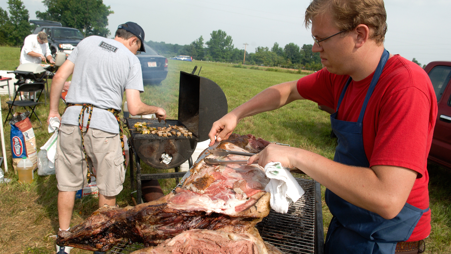 three men grilling meat