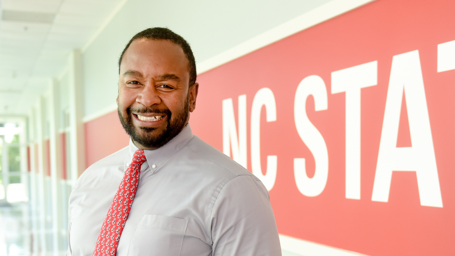 North Carolina Cooperative Extension Service Associate Director Travis Burke poses for a headshot in front of the NC State University logo.