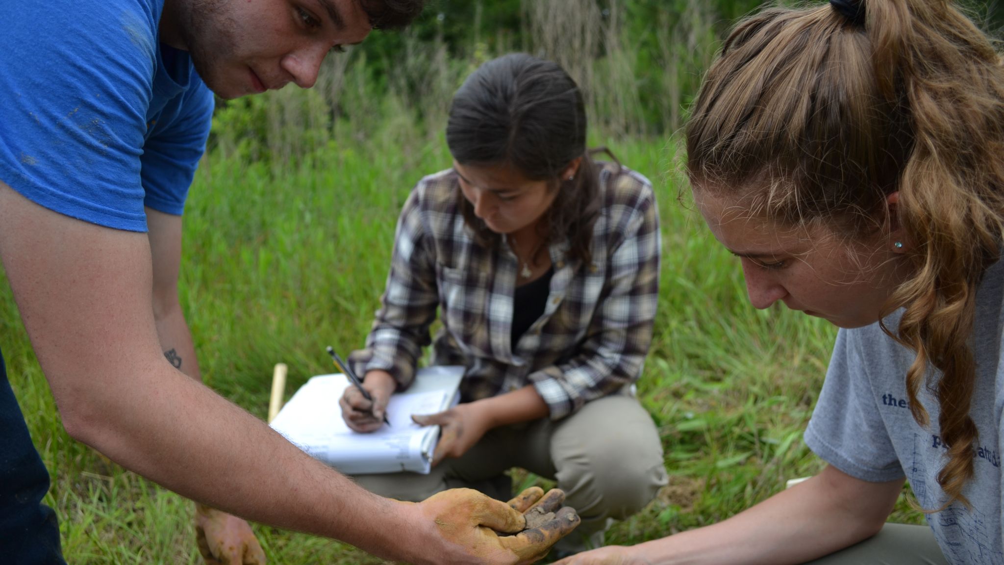 Three NC State College of Agriculture and Life Sciences students analyze soil in the field.