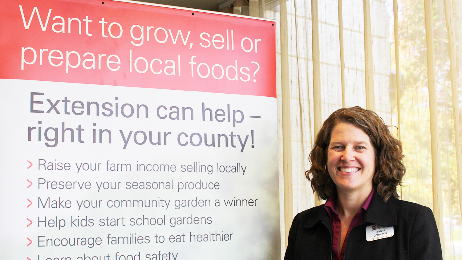 Joanna Massey Lelekacs beside an Extension local foods banner.