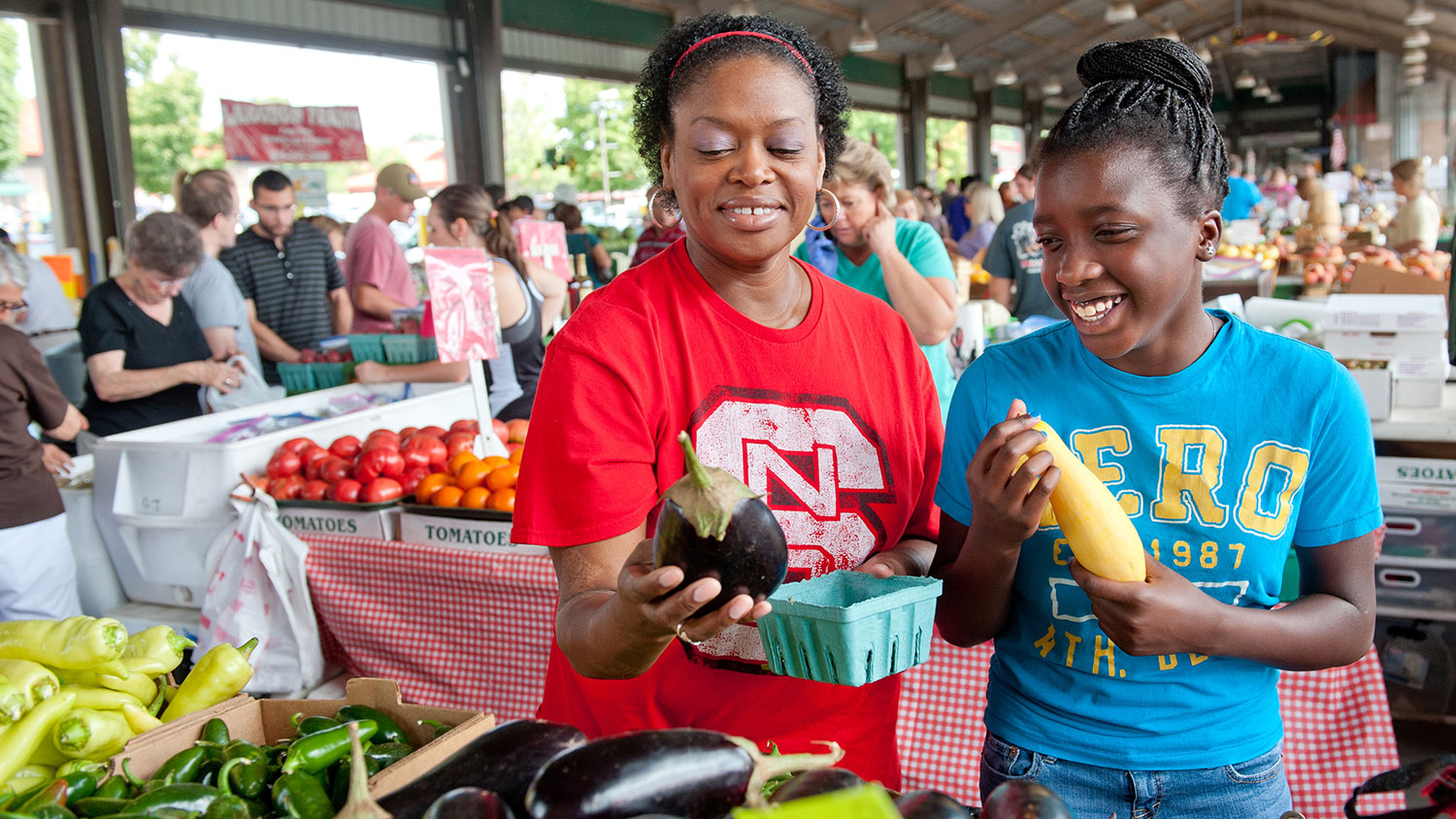 mother and daughter looking at fresh produce at farmers market