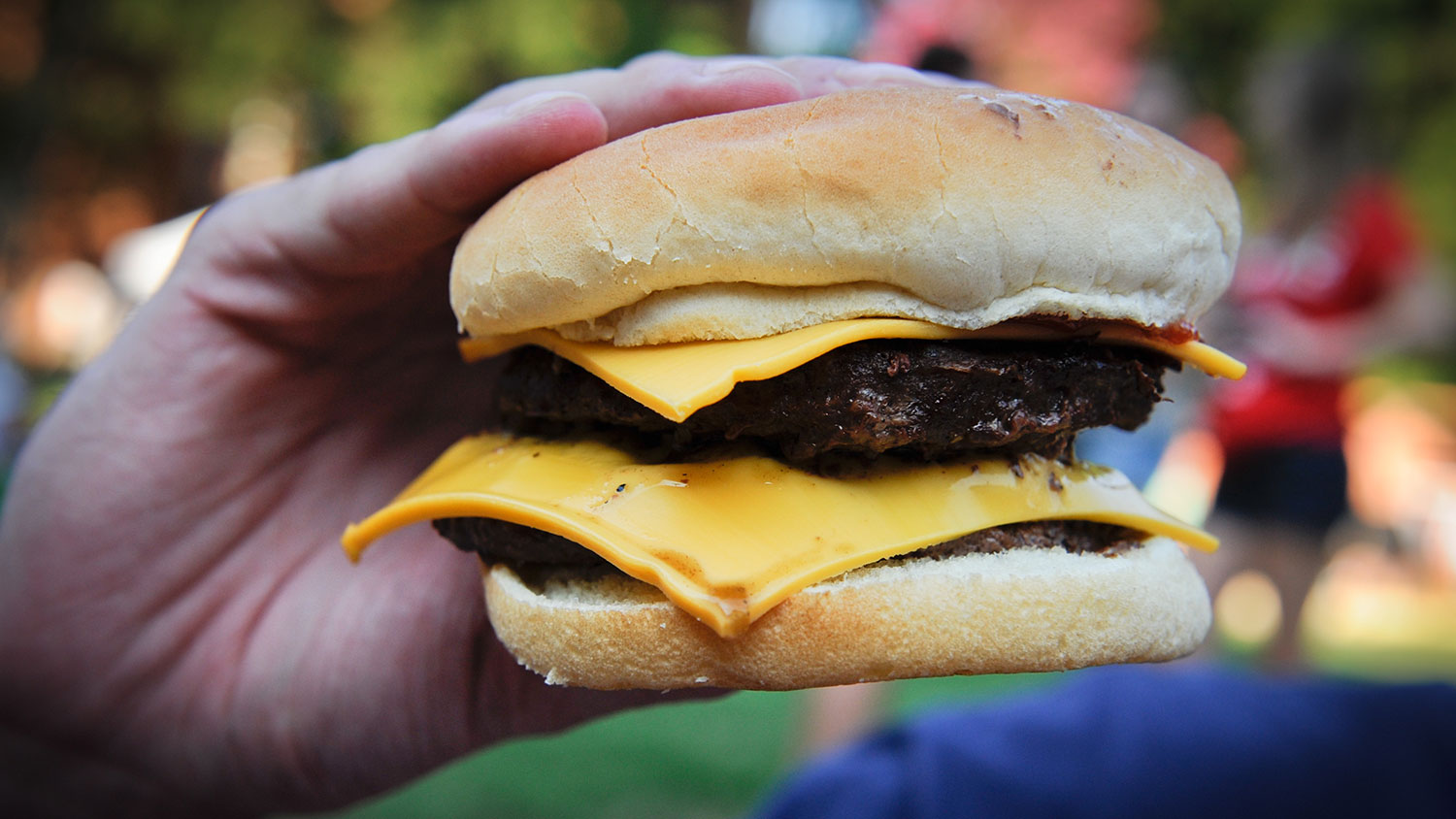 a hand holding a cheeseburger