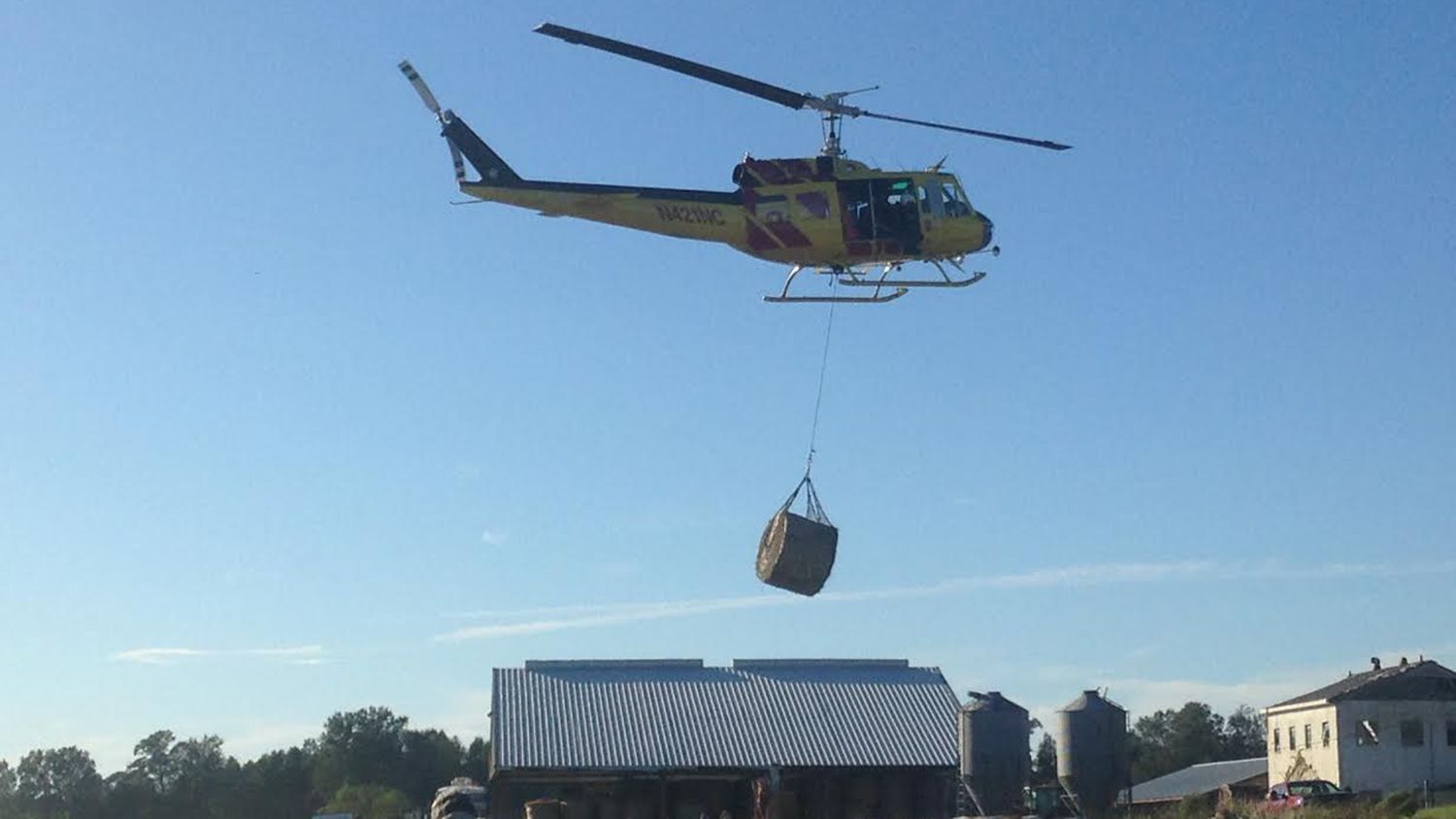 Helicopter lifting hay bale to animals on Cherry Research Farm in wake of Hurricane Matthew.