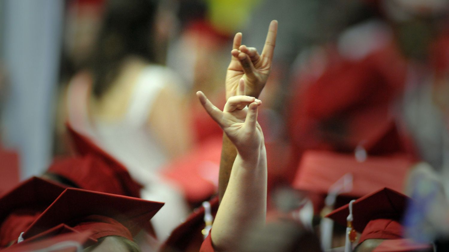 Graduating students raise their wolf hand high during commencement.