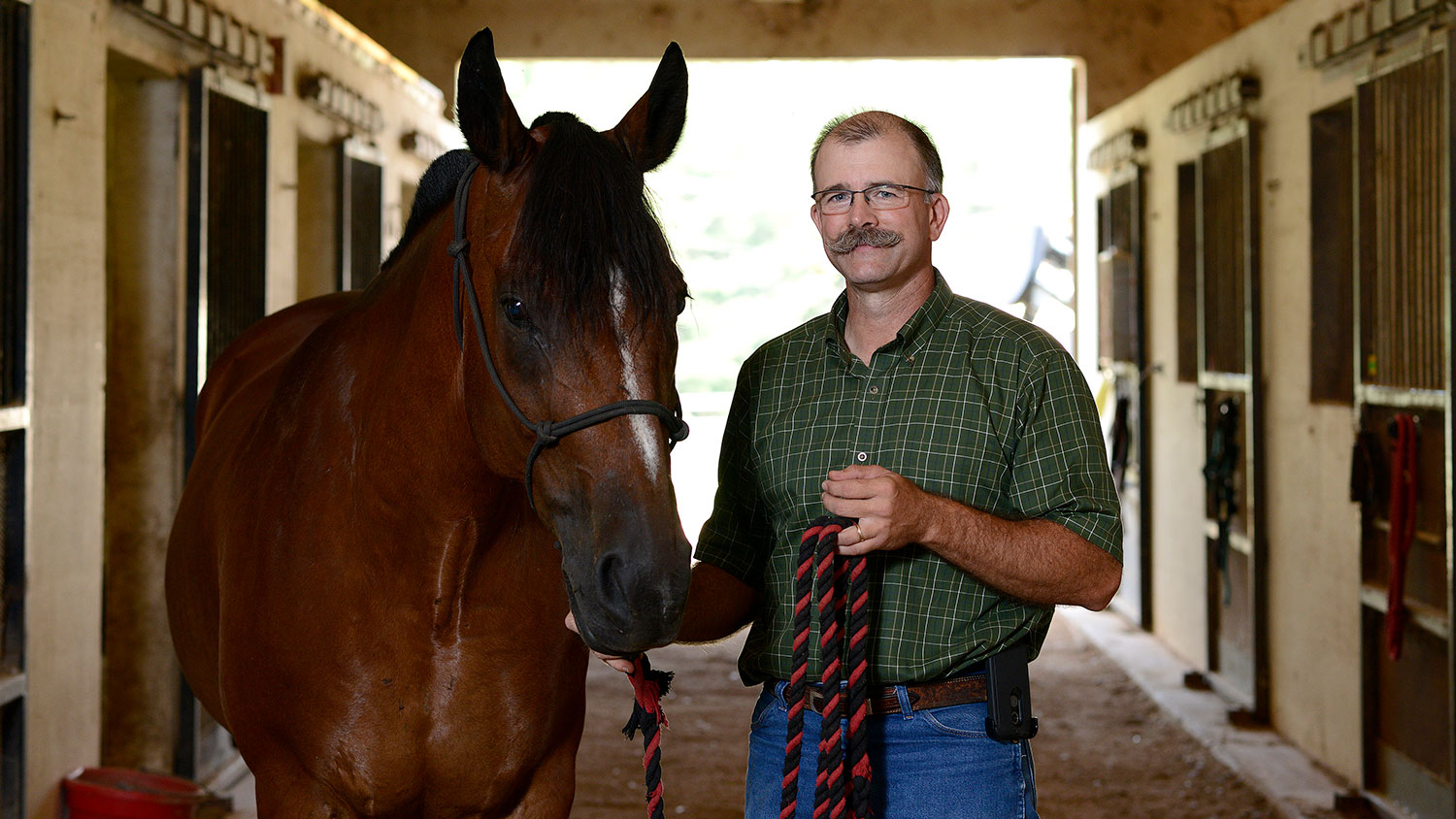 Paul Siciliano standing in a barn with a horse