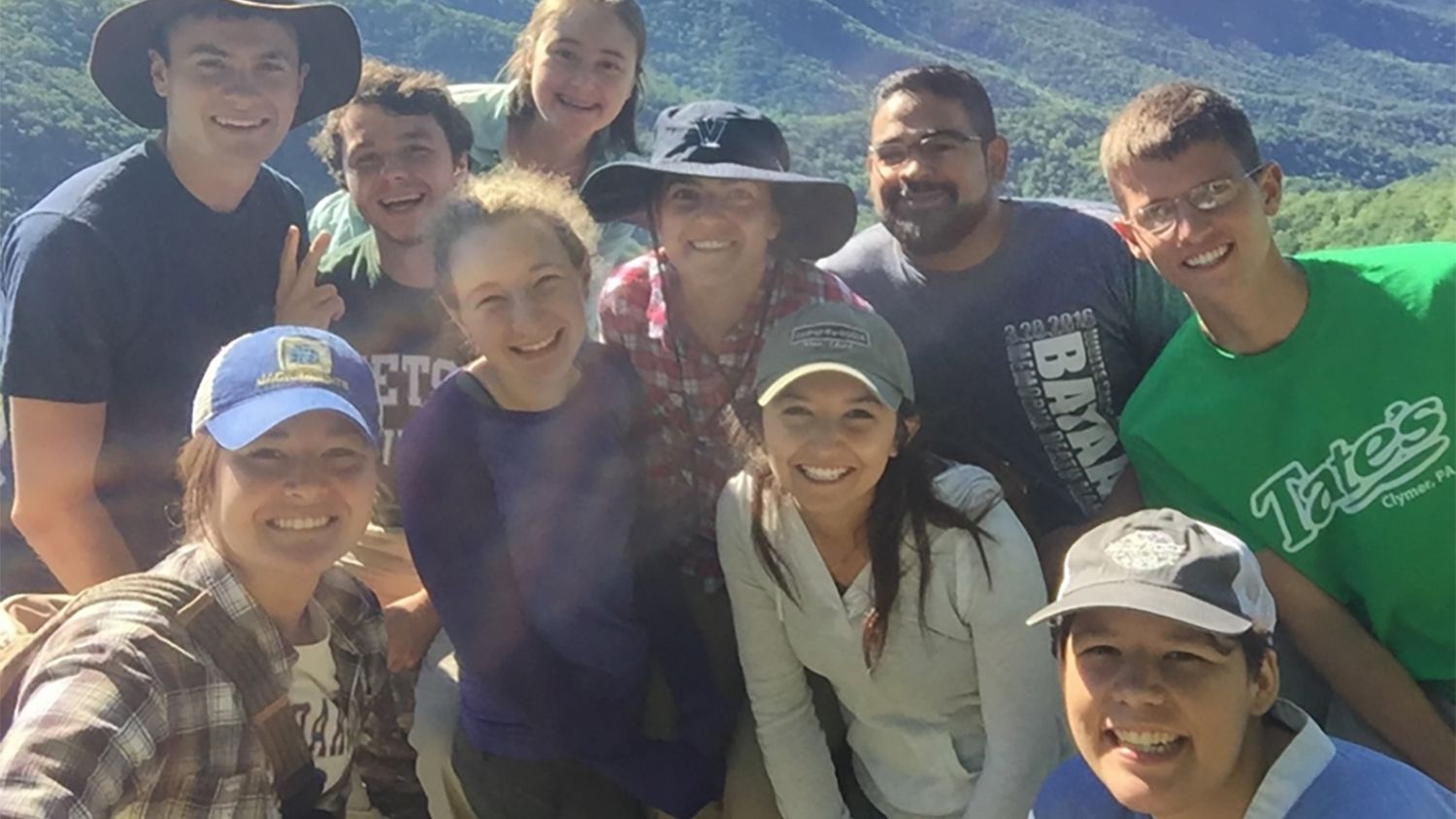 Group of 10 smiling students on a mountainside.