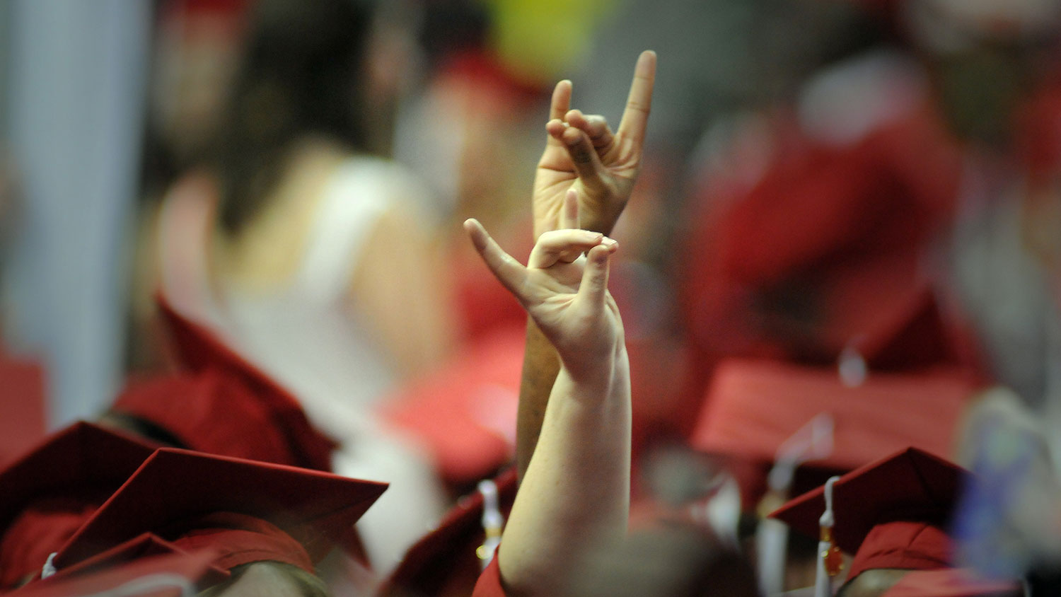 graduates making the wolf signal at NC State commencement