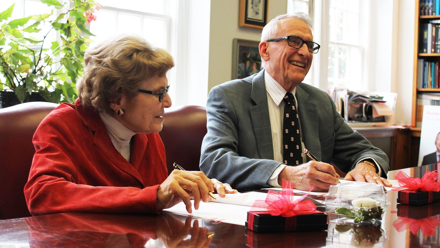 Marilyn and Charles Stuber, seated at a table, signing agreement