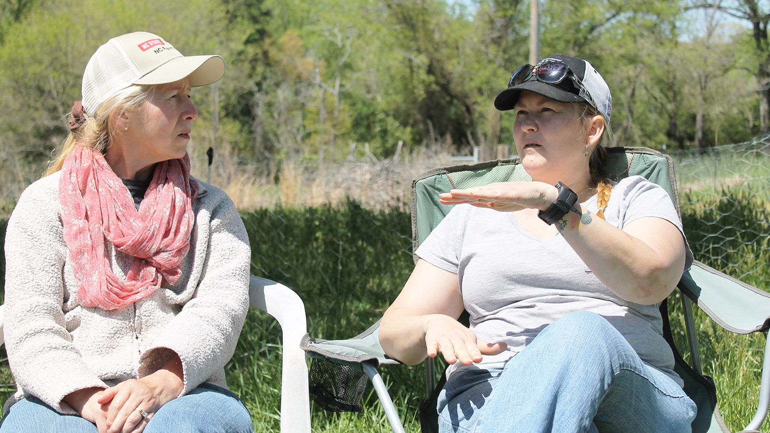 Two women sitting in lawn chairs, talking.