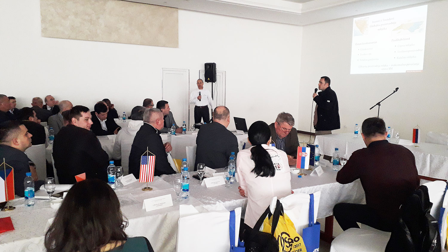 Photo of man delivering PowerPoint presentation to tables of people