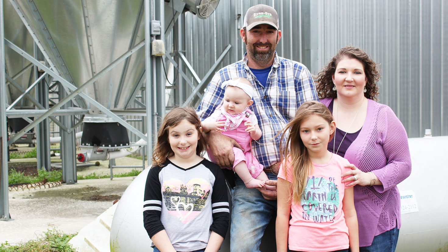 Family standing in front of farm equipment