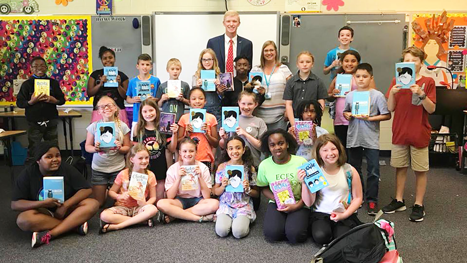 Class of elementary school students holding up books