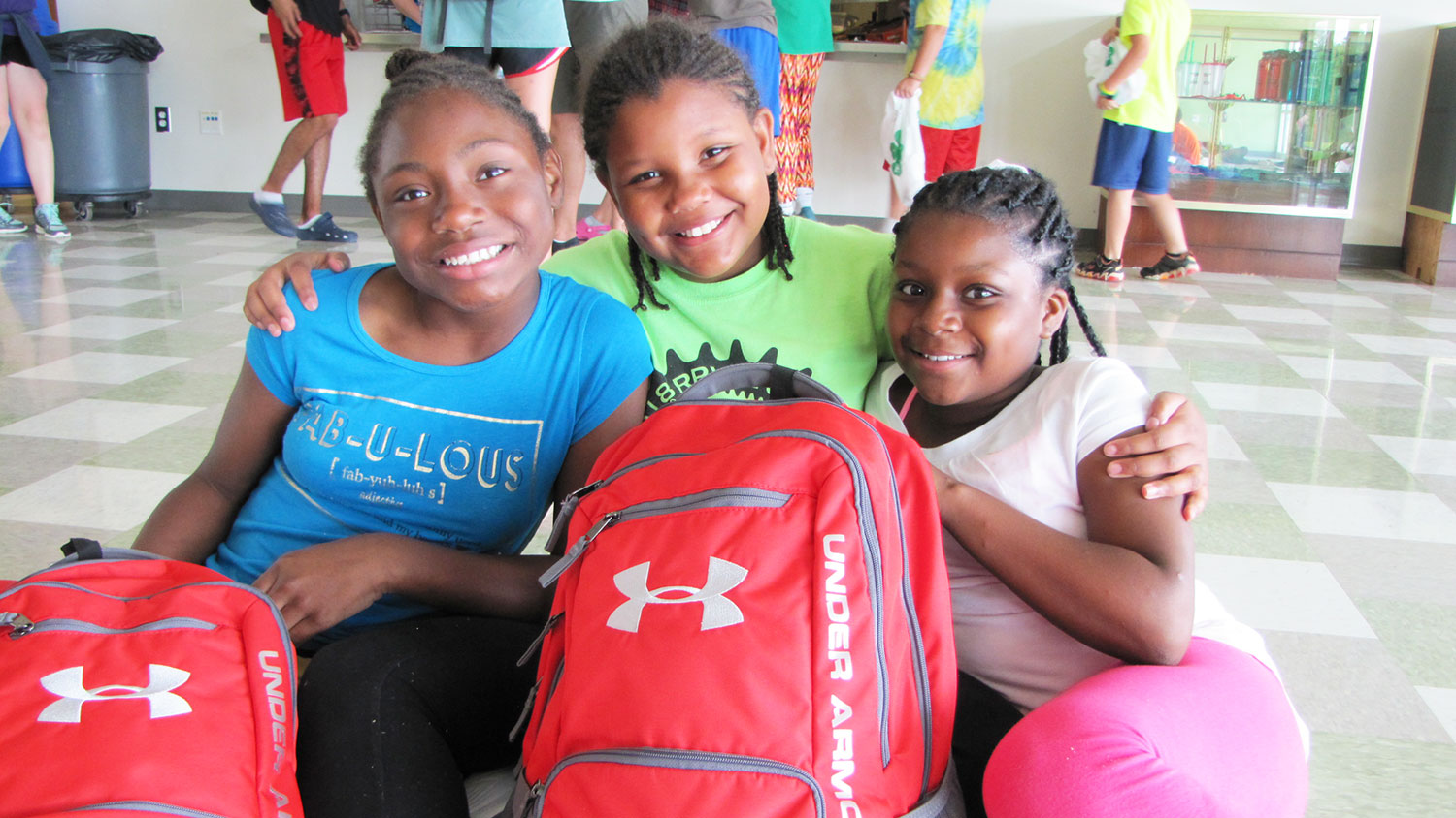 three girls sitting with a backpack