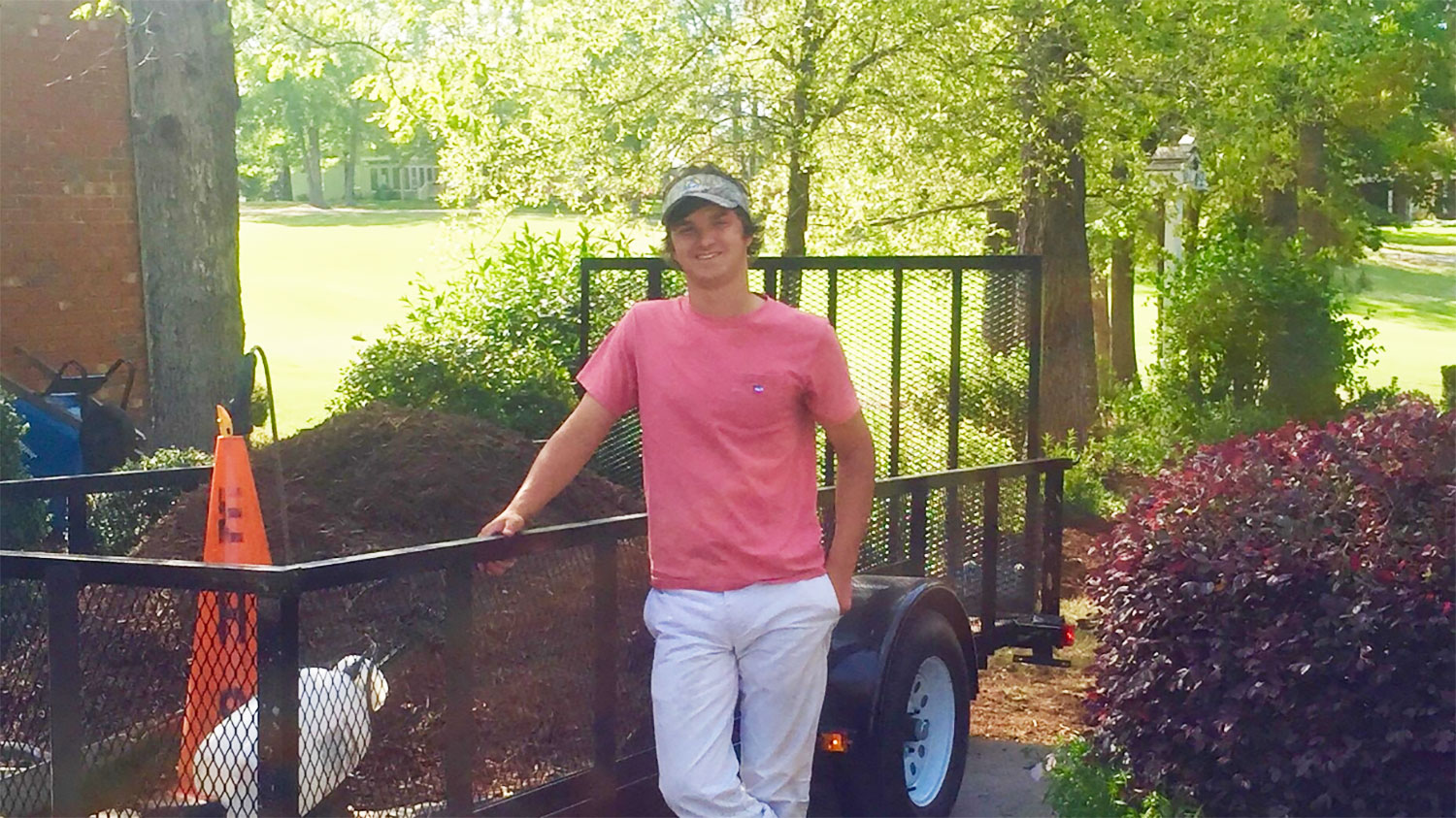 young man standing in front of a landscaping trailer