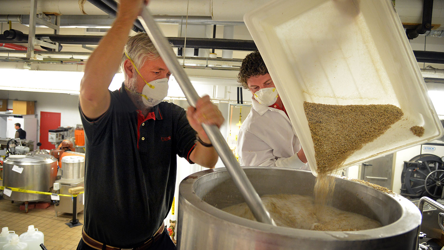 Dr. John Sheppard, coordinator for the undergraduate Bioprocessing Science Program, stirs malt while student Brandon Jackson (right) pours in the Schaub Hall lab.