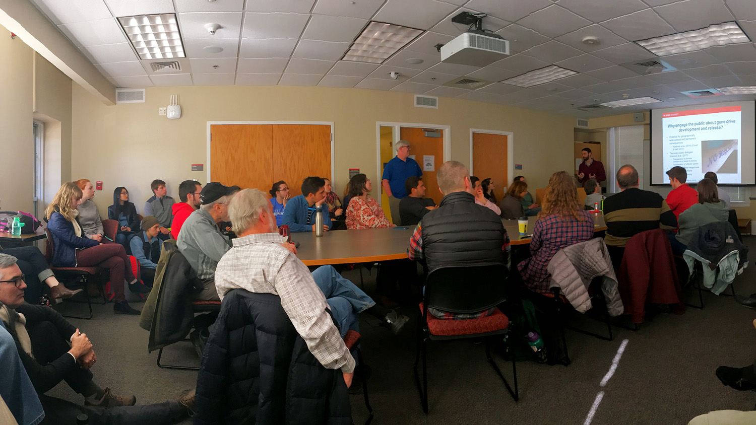 room full of people listening to a speaker give a presentation