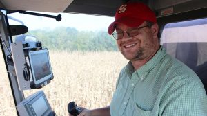 Smiling main inside a combine cab with computer equipment