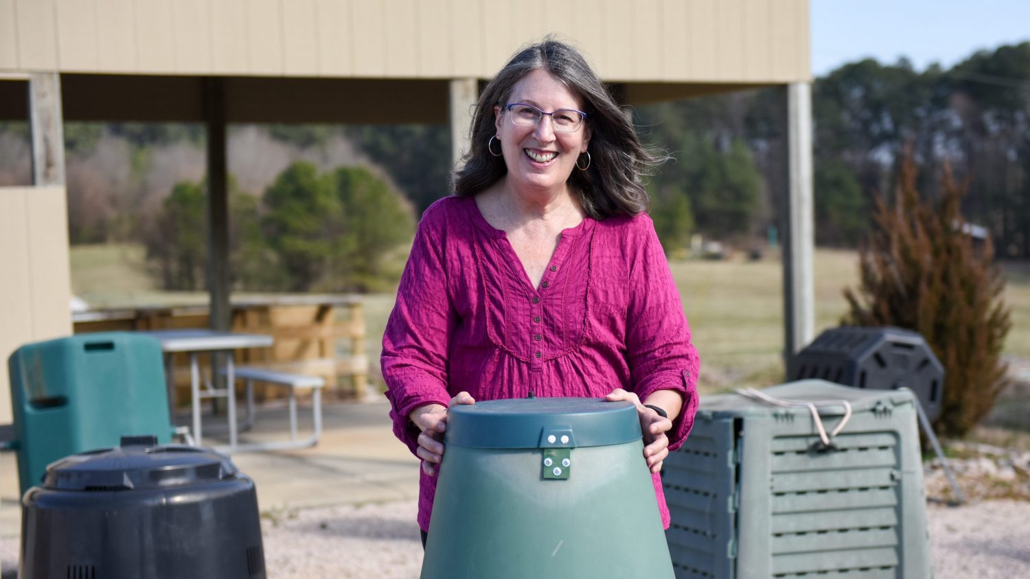 Women near a shed holding onto a vermicompost container