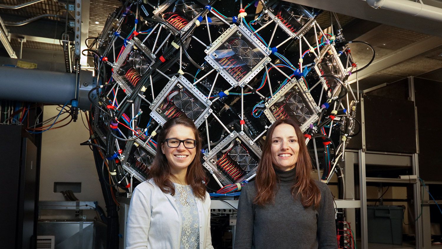 CALS Ph.D. student Gabriela Schroder and CALS professor of biochemistry FLora Meilleur stand in front of a complicated machine at ORNL.