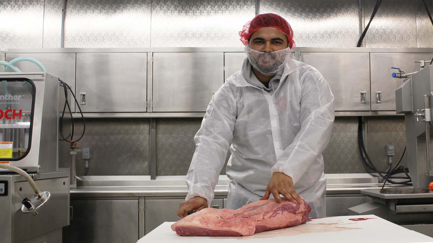 Man in lab coat cutting meat