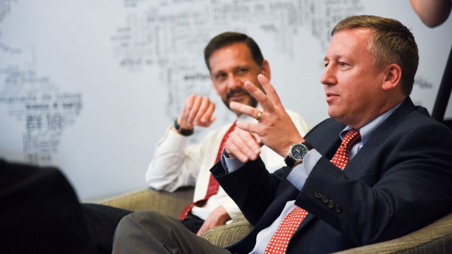 Two men sitting joining in a larger conversation.