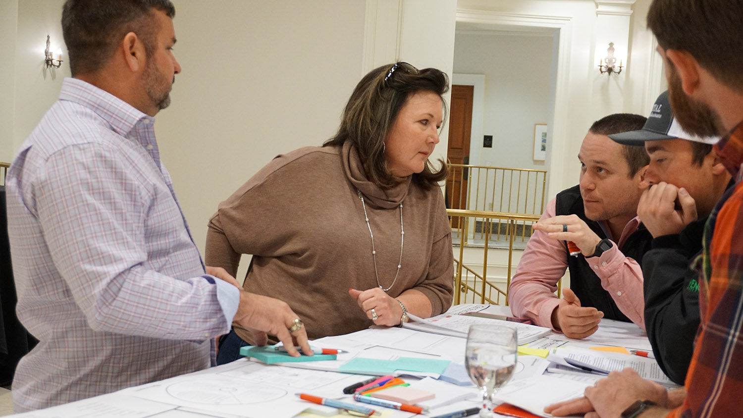 4 people talking as they stand around a table