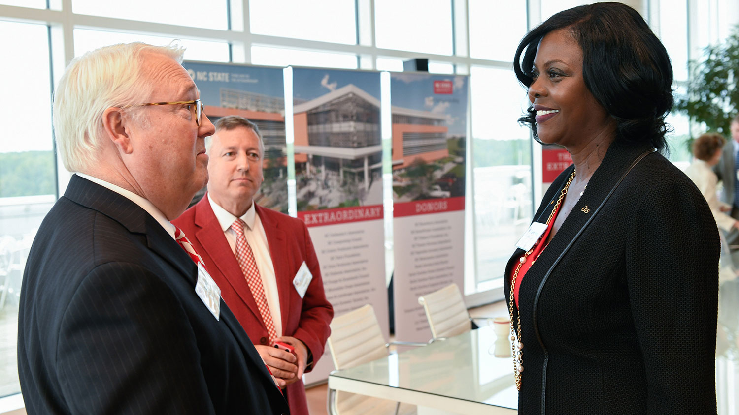 Chancellor Randy Woodson, Dean Richard Linton and USDA ARS Administrator Chavonda Jacobs-Young talking near a Plant Sciences Building display
