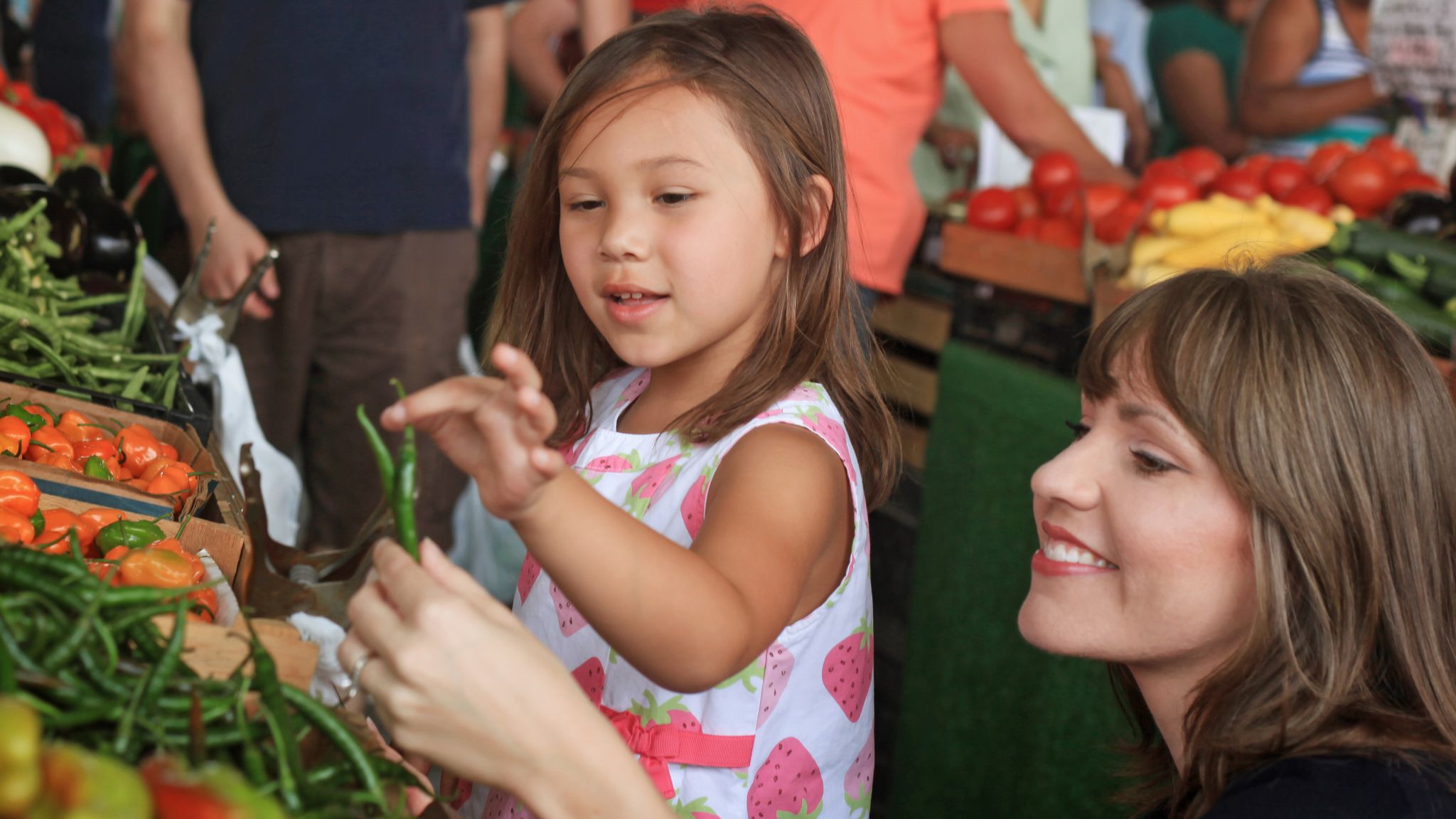 Woman and girl looking at beans at a farmers' market.