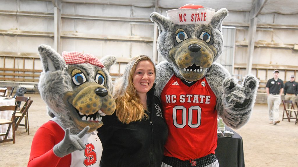 CALS alumna posing with Mr. and Mrs. Wuf at Tailgate.