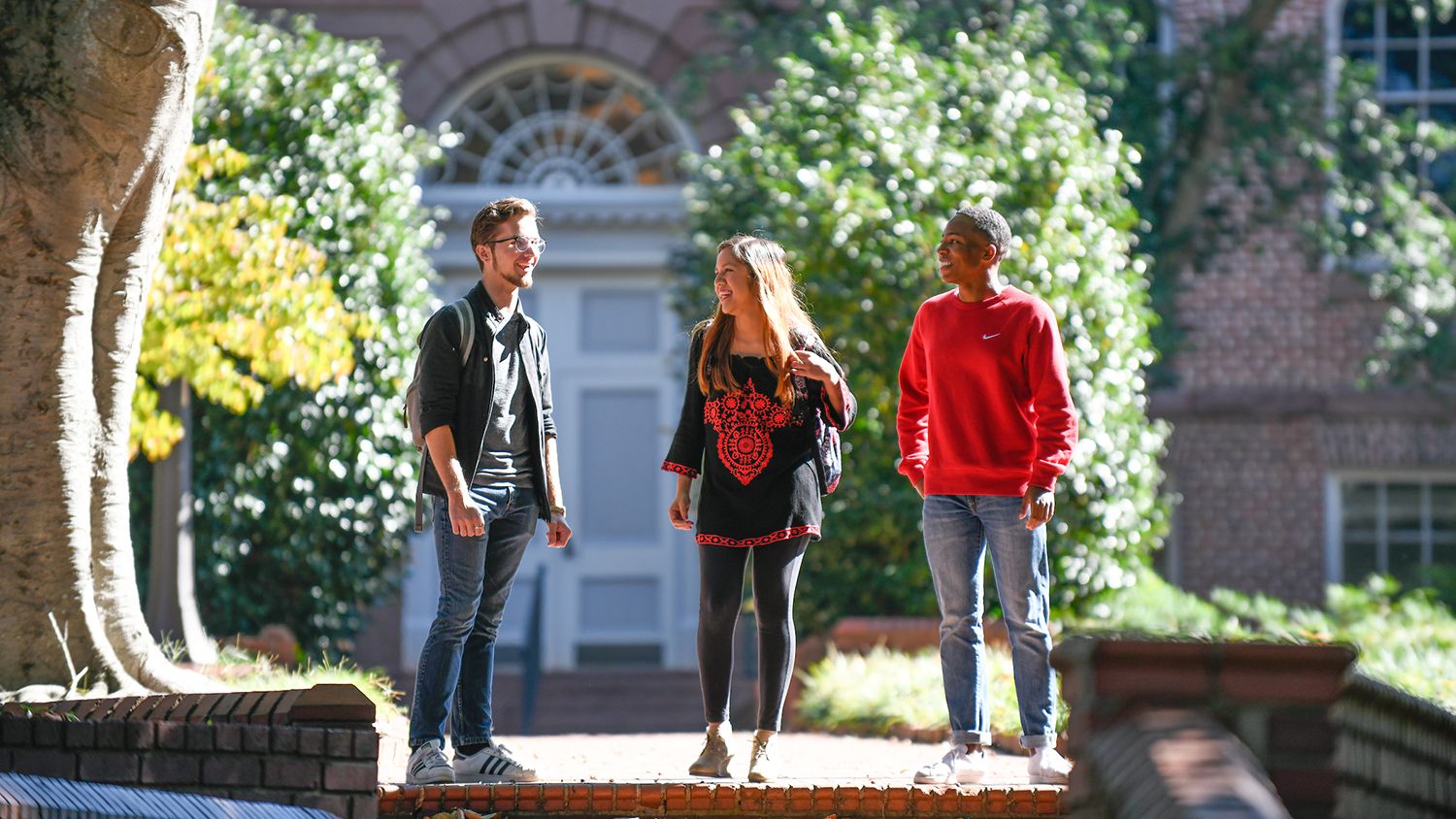 Three students talking outside on sidewalk
