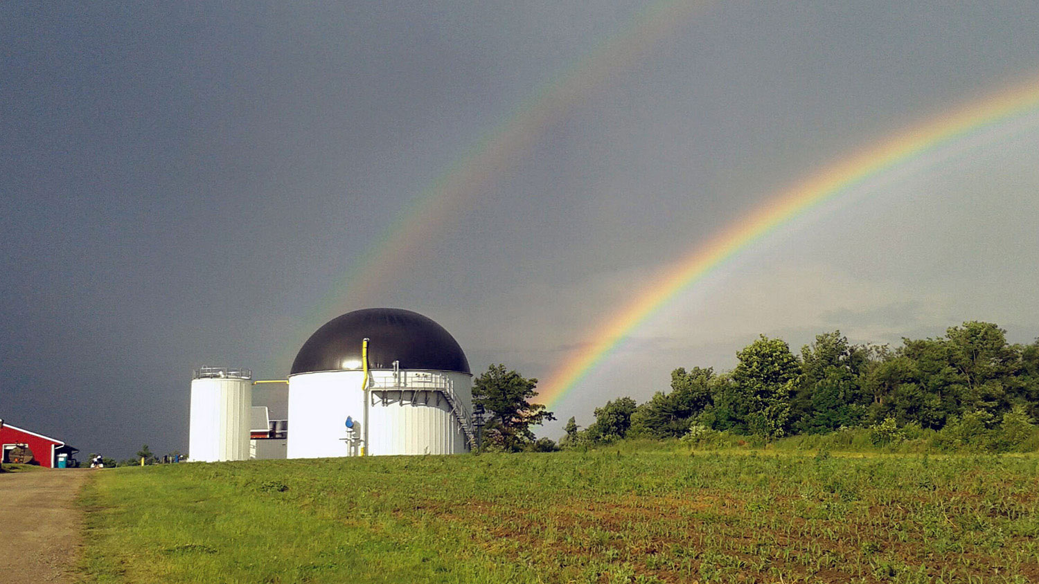 Double rainbow with cloudy skies at a Dairy Farm.