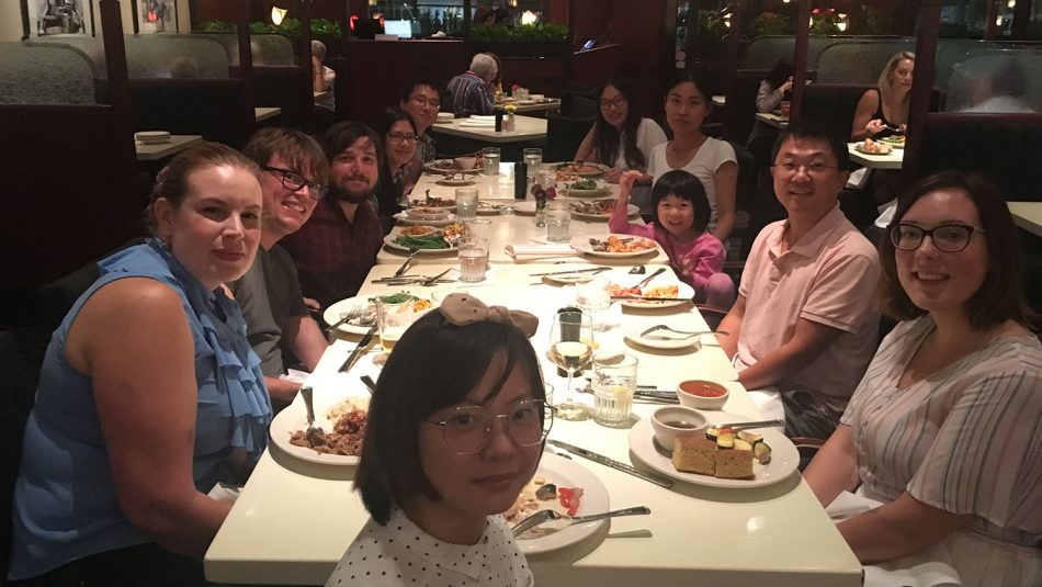 The members of the Liu Lab around a large table with a white tablecloth during a celebratory meal.