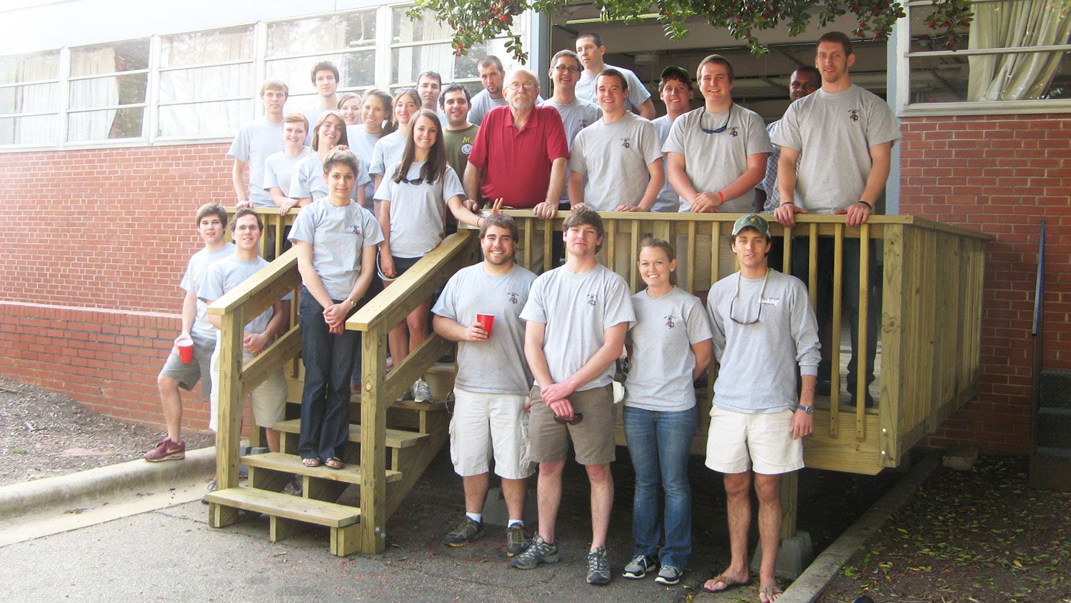 Students and their professor stand on an outdoor deck