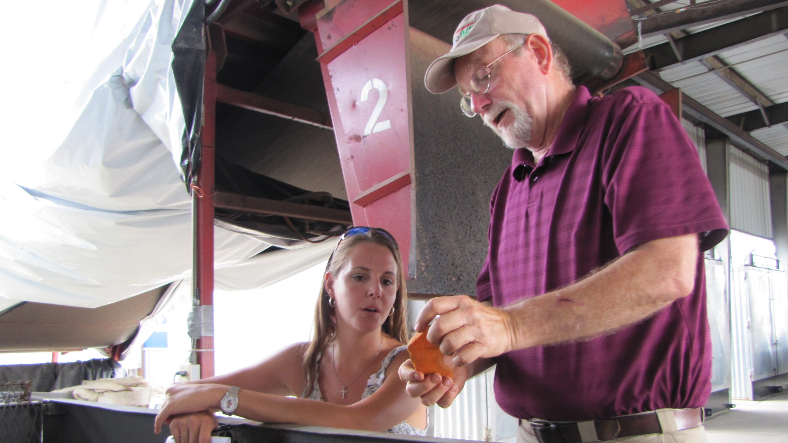 With woman looking on, man examines a peeled sweet potato