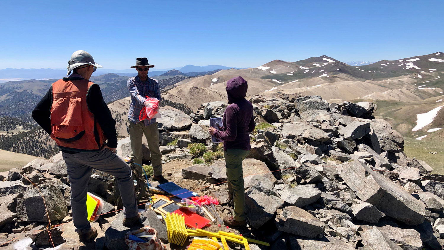 Three people standing on top of a mountain