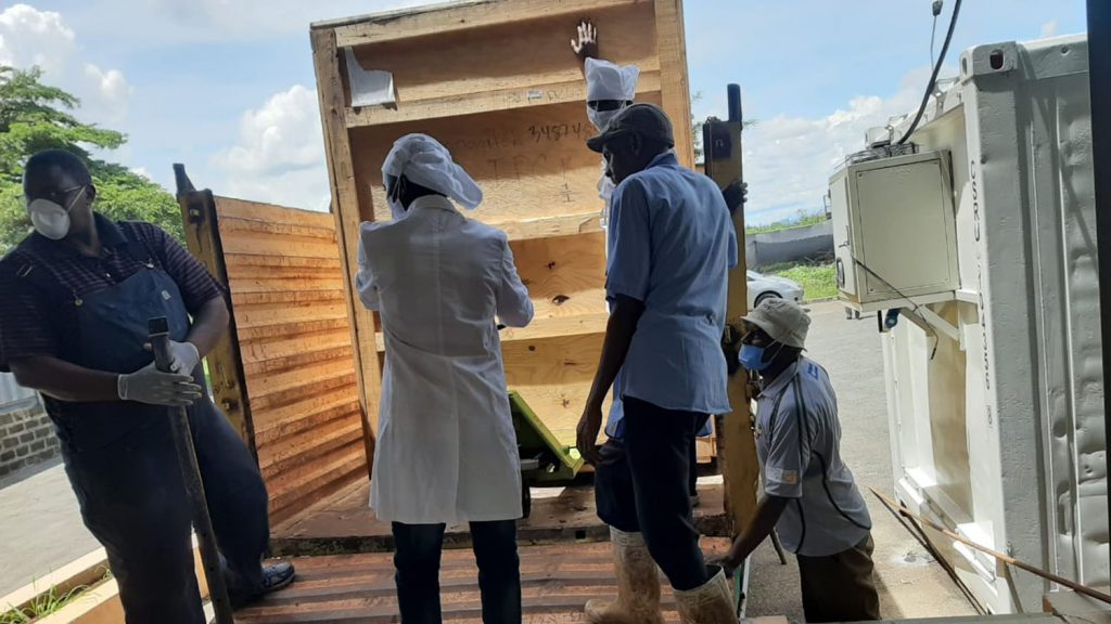 A group of five men unloading a wooden crate.