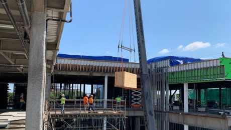 A wooden crate being hoisted by a crane into a building.