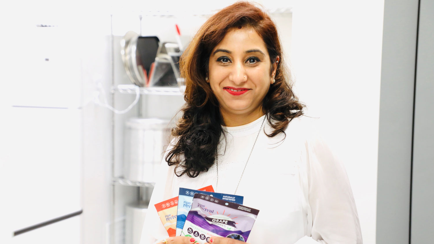 An Indian woman holding three packages of gummies