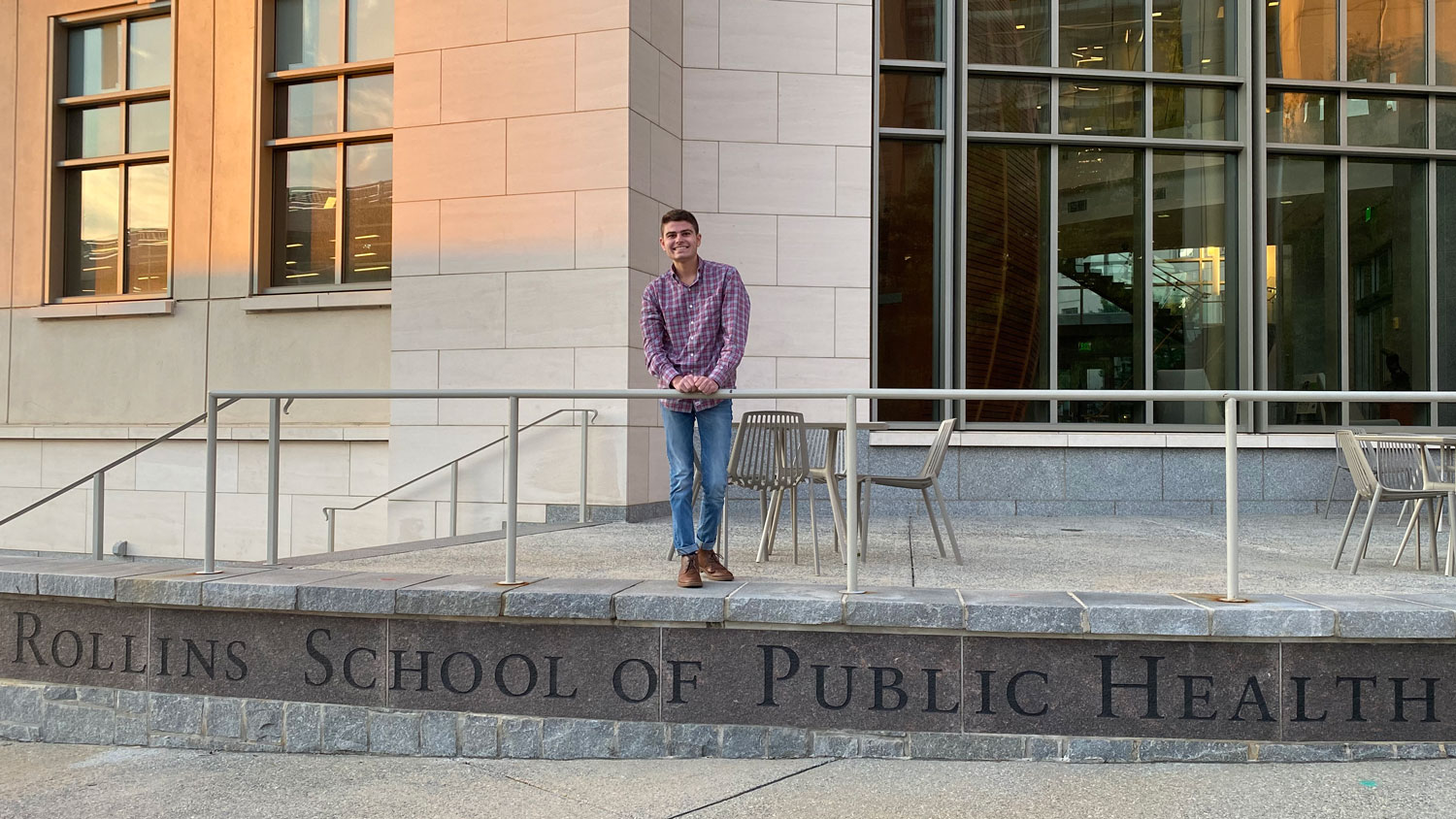 A young man standing on the steps of Emory University's School of Public Health