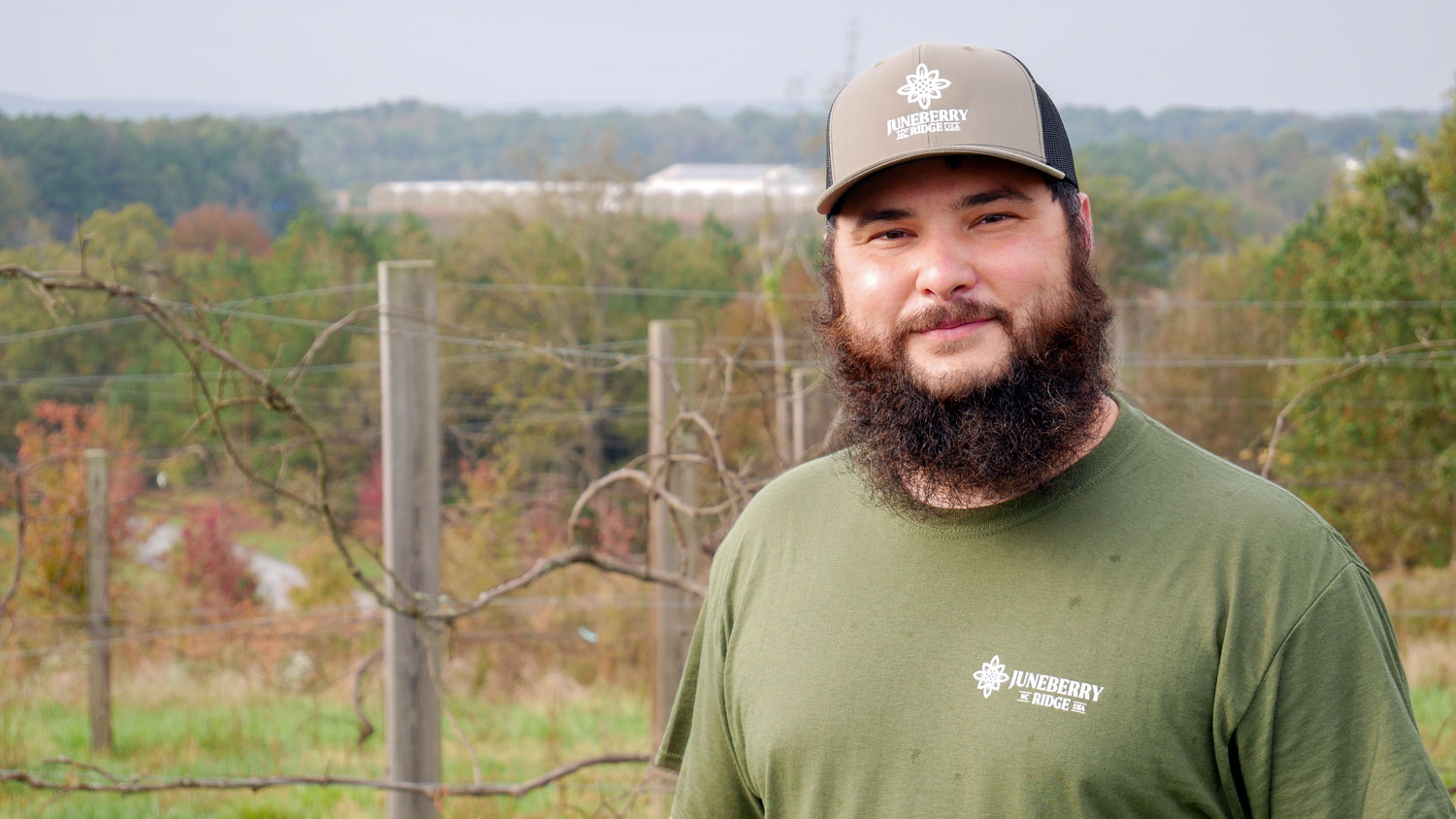 A man standing in field with hills in the background