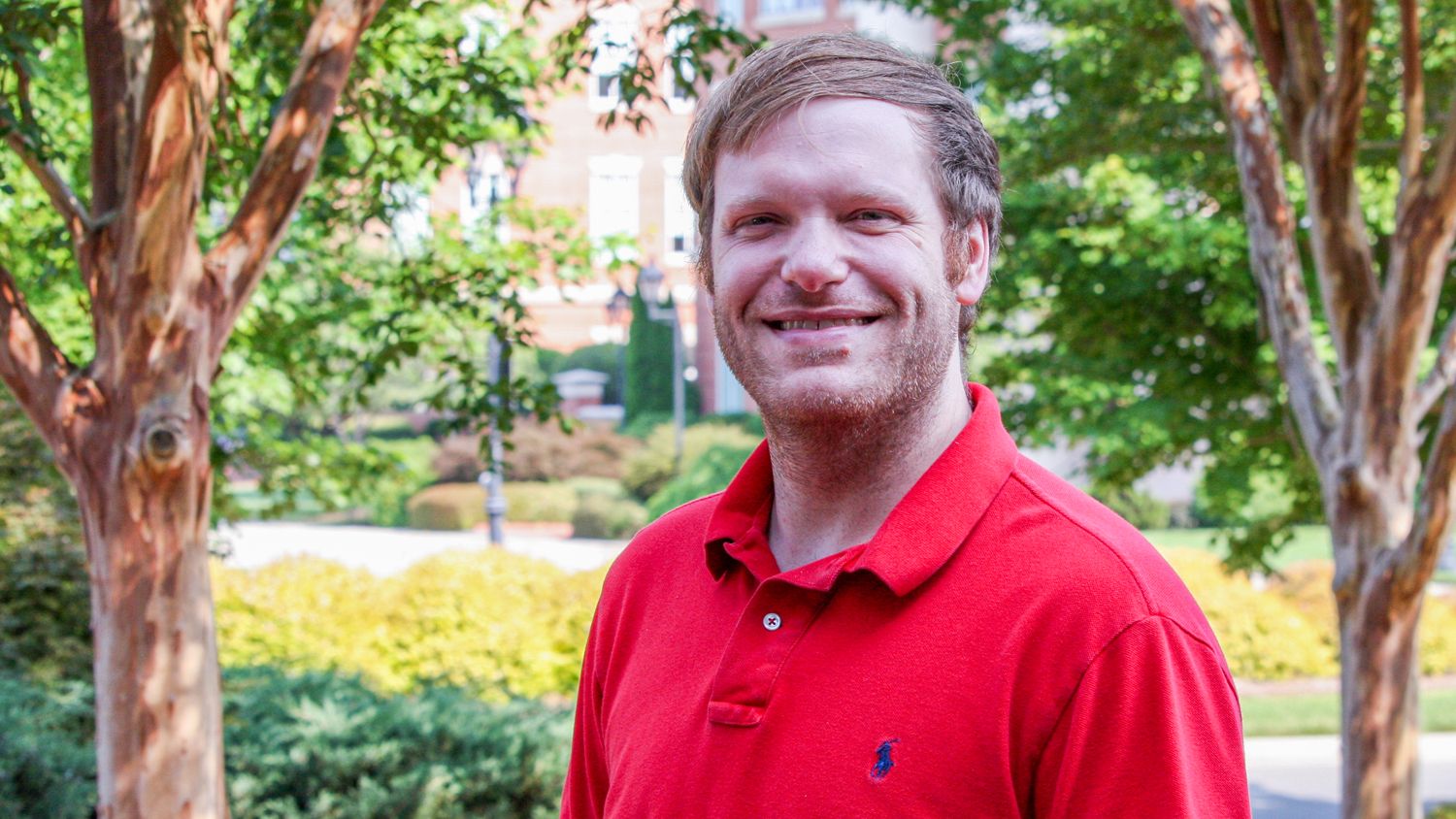 A young man wearing a red polo shirt outside