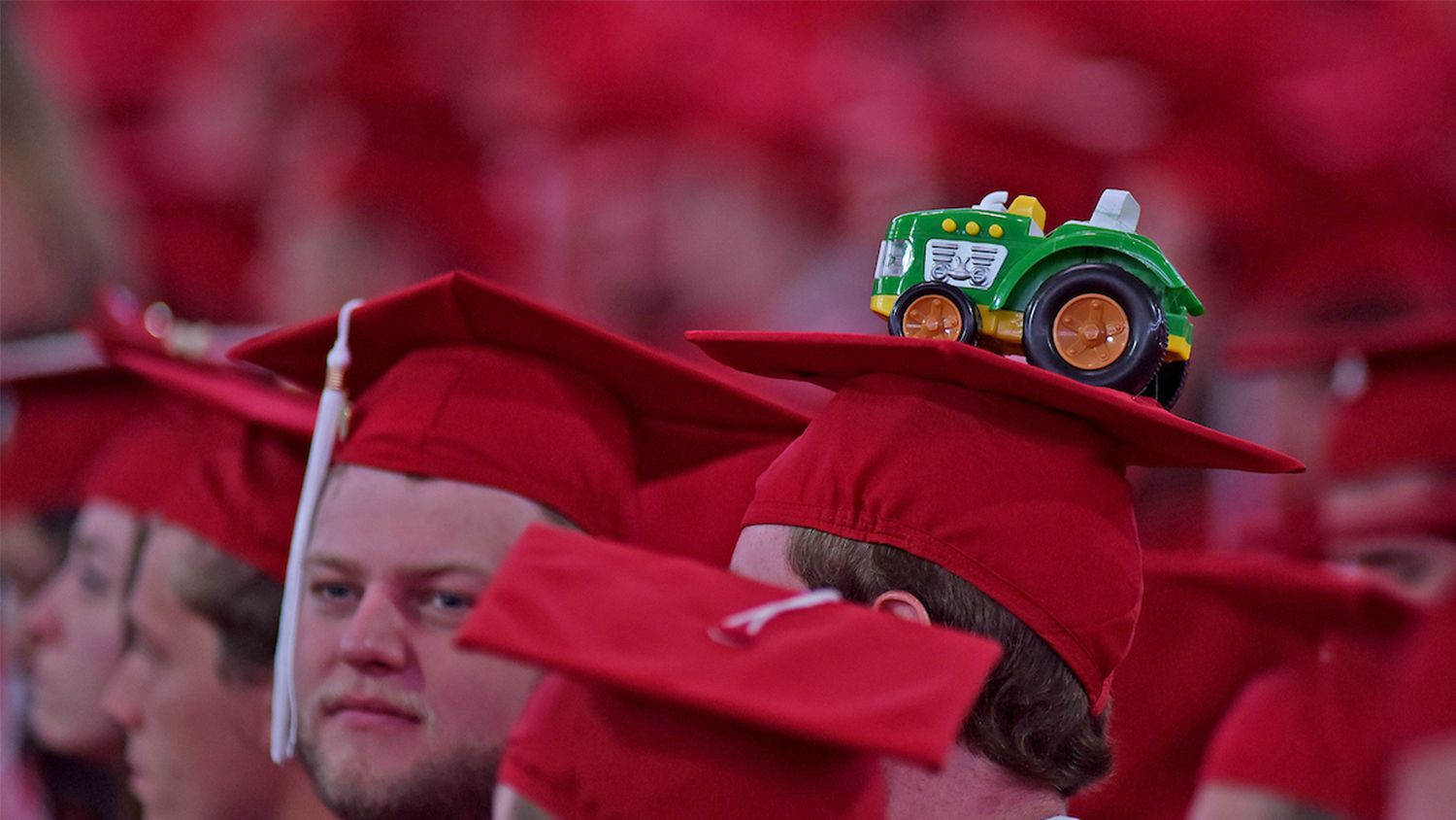 red graduation caps with a tractor on top of one cap