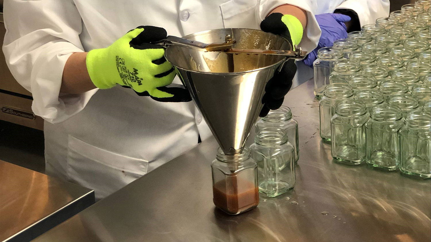 Caramel sauce being poured into glass jars.