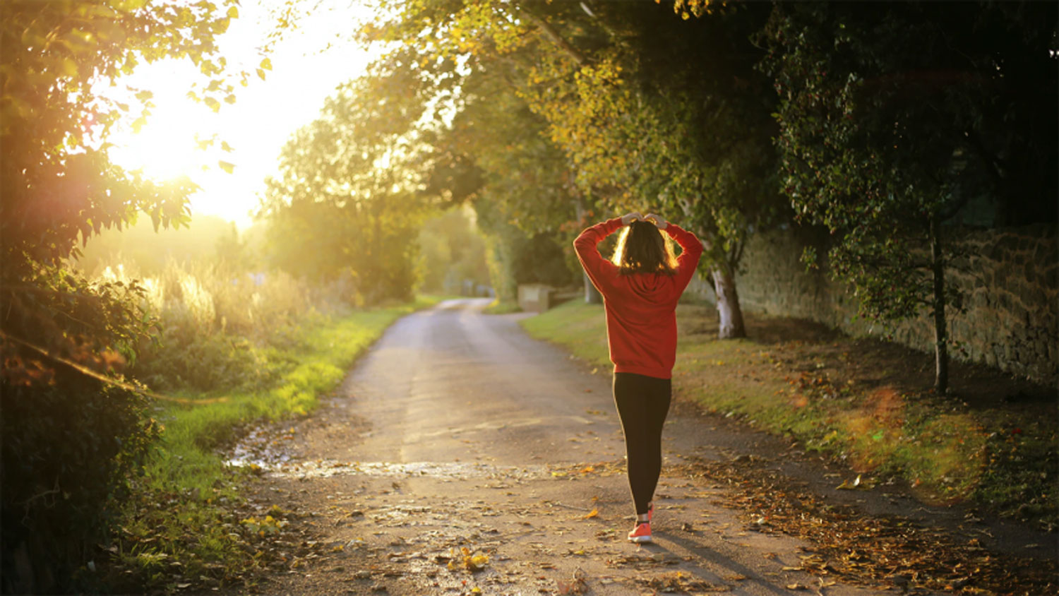 A woman walking on a path with her hands on her head