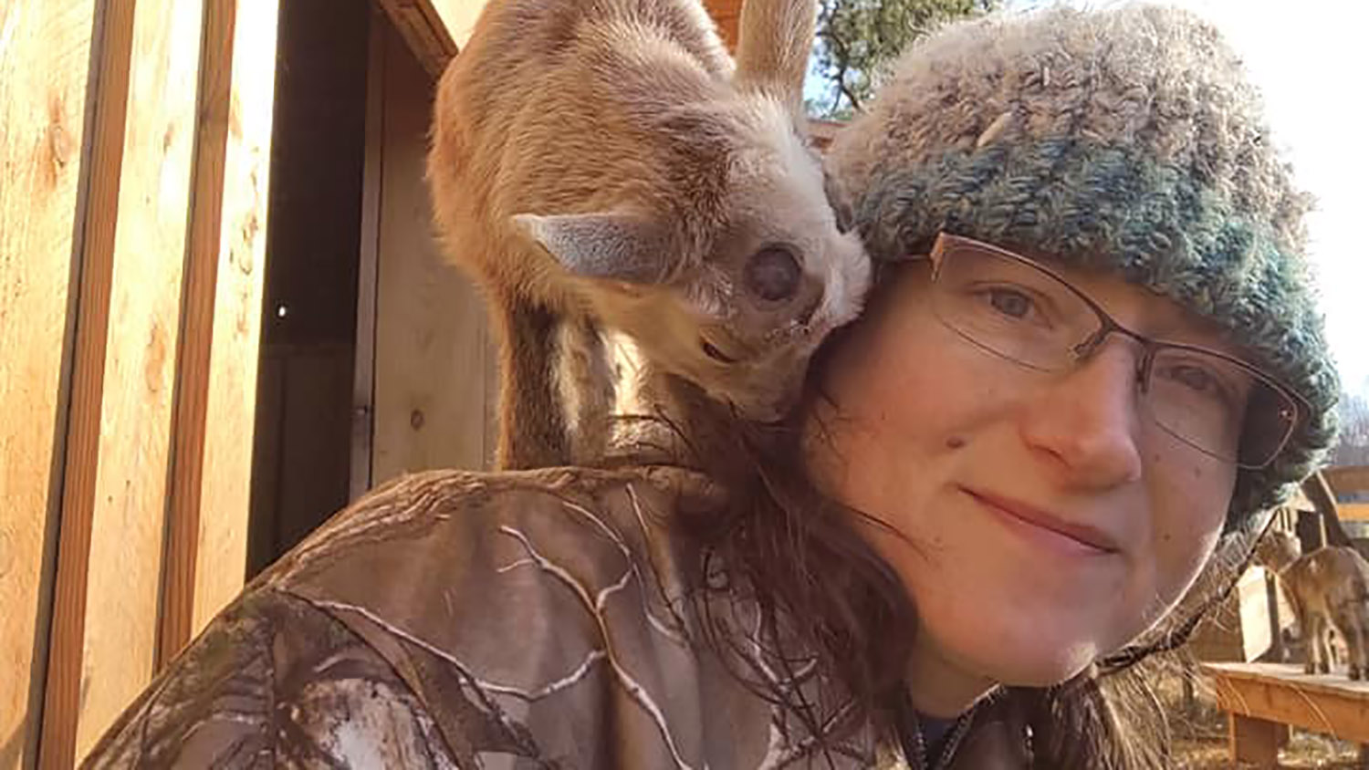 Woman with small goat on her shoulder